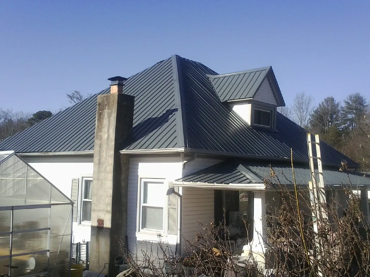 Dark blue standing seam metal roof on a white farmhouse with dormer — Slate & Tile Roof Repair by Roofing Brothers in Charlemont