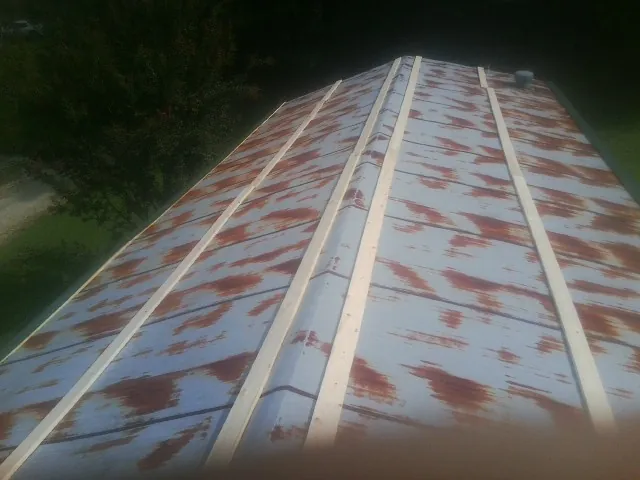 Rusted metal roof panels with new wood purlins before replacement — Storm Damage Roof Repair in Charlemont by Roofing Brothers