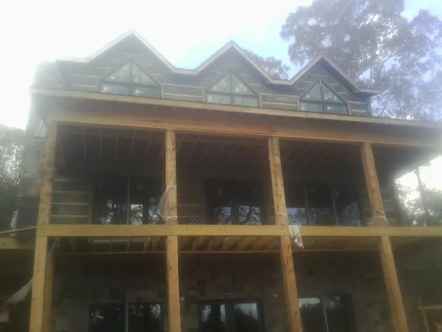 Dormers and porch framing on a large log home under construction — Roof Coating work by our crew in Charlemont