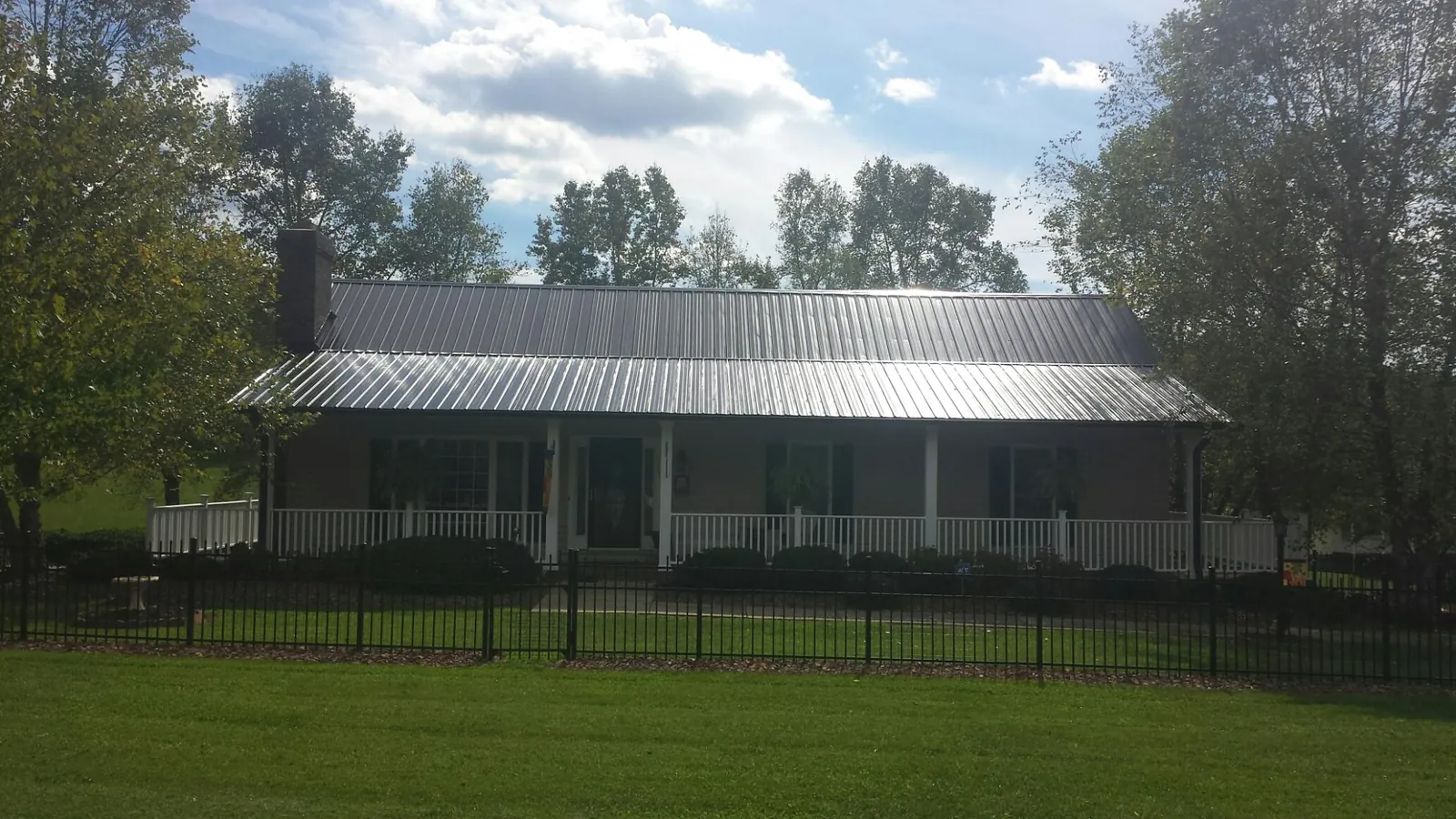 Gray metal roof on a brick ranch with a full width front porch — Gutter Guard Installation work by our crew in Charlemont