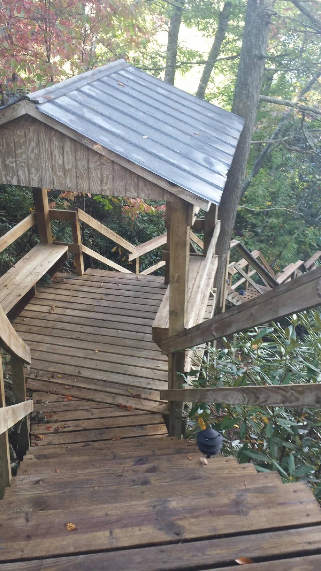 Metal roofed shelter over wooden steps on a wooded walkway — Skylight Repair & Installation work by our crew in Charlemont