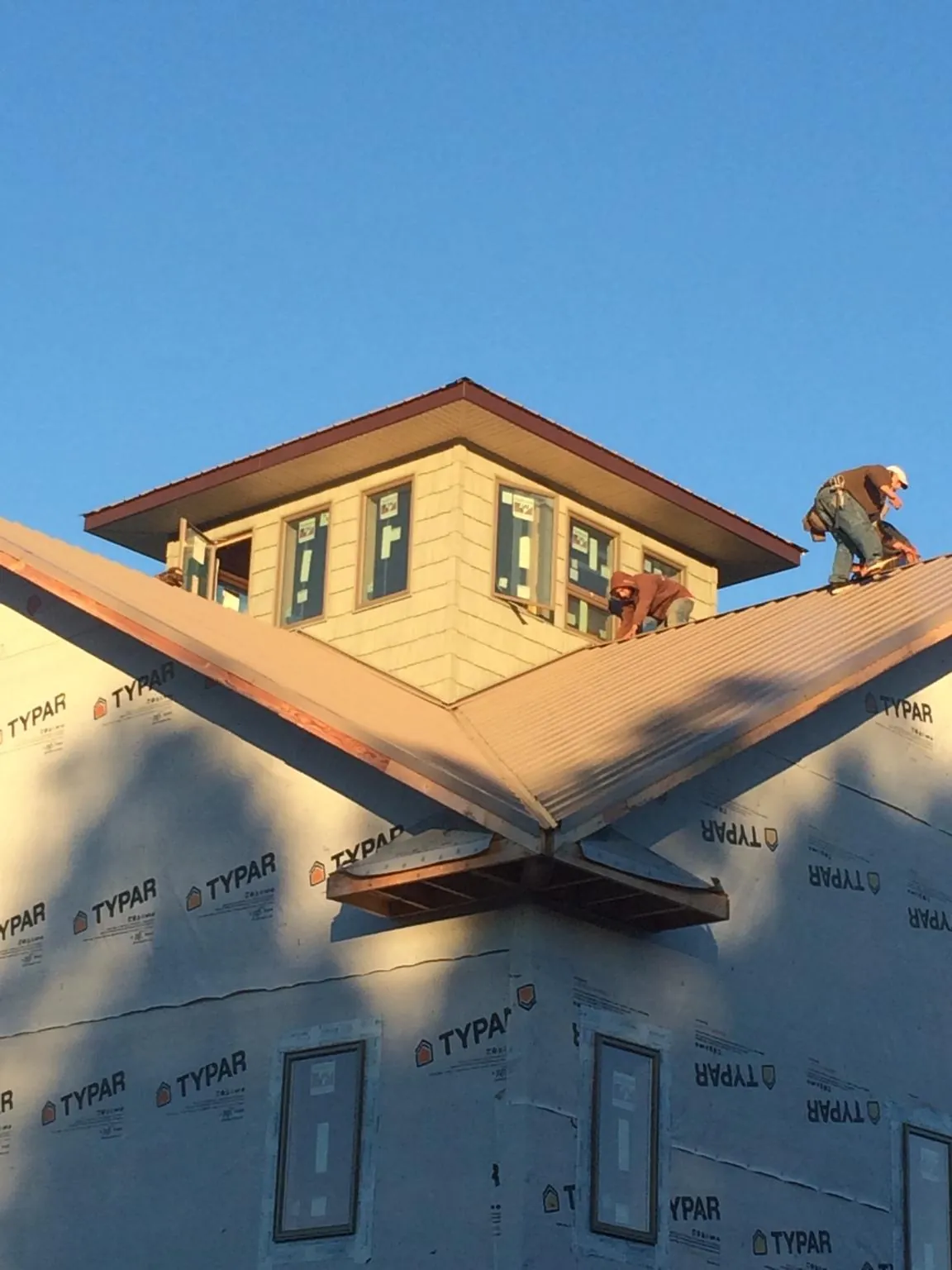 Roofers working around a rooftop cupola on a new metal roof at sunset — Roof Waterproofing in Charlemont by Roofing Brothers